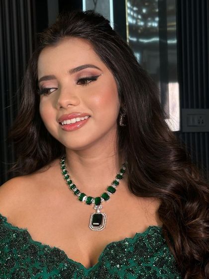 A full view of the client, her green gown perfectly matching the emeralds in her necklace.