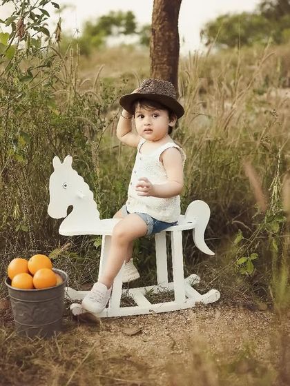 This little cowboy is tipping his hat. The rustic, natural setting and the warm, gentle light make this outdoor portrait feel so timeless and full of character.