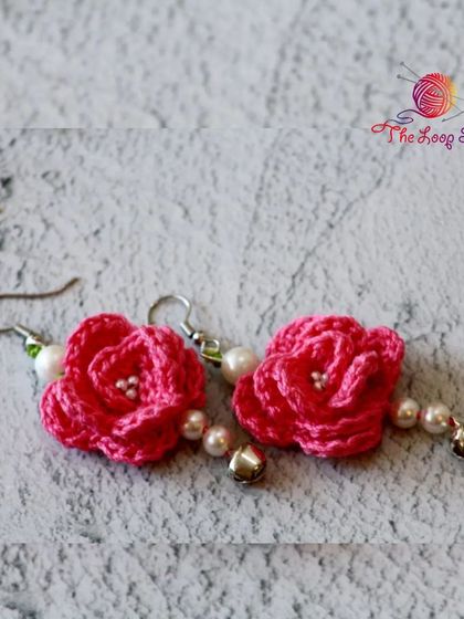 Elegant pink rose crochet earrings, detailed with small pearls and a tiny bell for a delicate look.