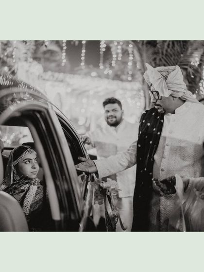 The Vidaai. A poignant black and white shot of the groom helping his bride into the car, marking the beginning of their new journey together.