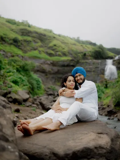 A peaceful moment shared by the couple, sitting on a rock amidst the natural beauty of their pre-wedding shoot location.