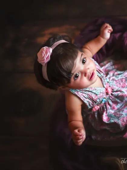 An artistic overhead shot of the baby looking up from the basket. This perspective highlights her beautiful eyes and captures a moment of sweet connection with the camera.