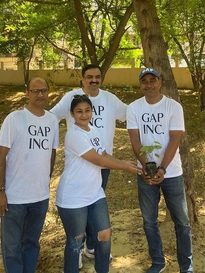 The Gap Inc. team holds up a sapling, ready to plant it and contribute to the biodiversity of the Aravali Creek restoration site.