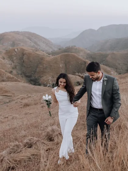 A candid moment of the couple walking hand-in-hand through a field of golden grass, capturing the feeling of a shared journey in a beautiful, natural setting.