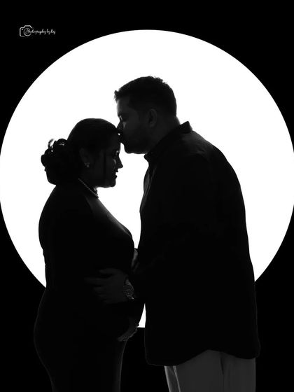A classic silhouette of a couple against a full moon backdrop, capturing a tender kiss on the forehead.