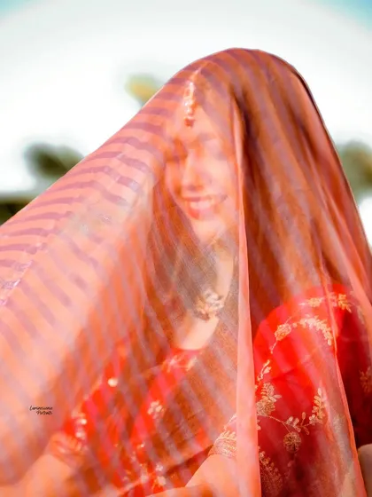 A beautiful, soft-focus shot of the bride smiling behind her veil, creating an ethereal and romantic mood.