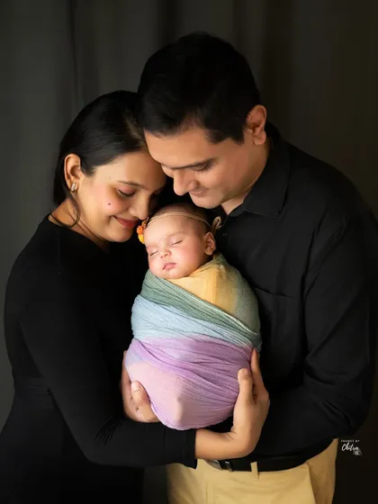 A more intimate version of the family portrait, with the parents holding their baby close. This pose emphasizes the feeling of protection, warmth, and family unity.