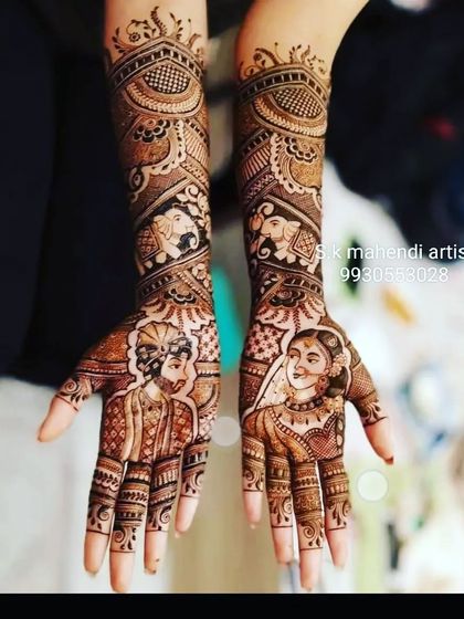 A clear and detailed portrait of the bride and groom. The arms are decorated with elephant motifs and traditional patterns.