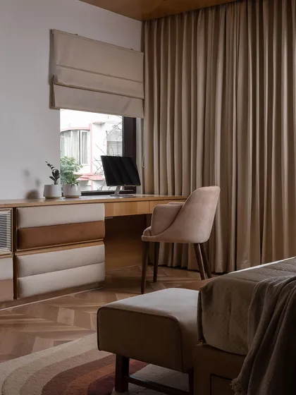 The master bedroom at Haus of Aureus is a cocoon of warmth, with wood-paneled walls and a custom upholstered bed. The herringbone wood flooring adds another layer of texture and sophistication.