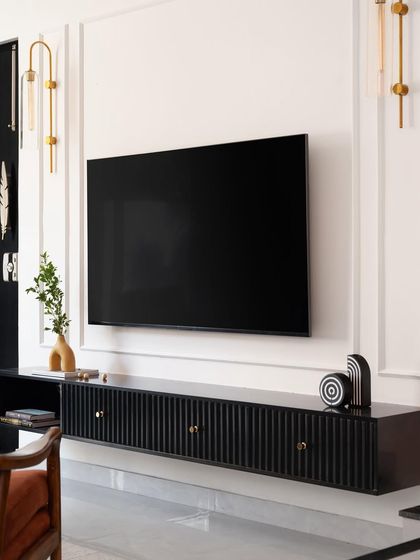 A full view of the black statement TV unit, flanked by modern gold wall sconces that complement its sophisticated design.