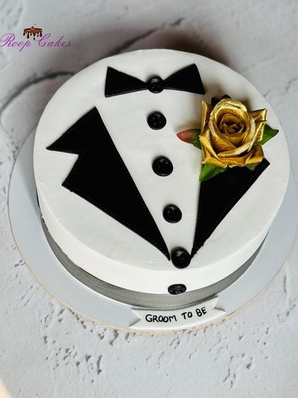 A dapper cake for the groom-to-be. This design cleverly mimics a tuxedo, complete with a bow tie and a golden rose boutonnière, perfect for a bachelor party or celebration.