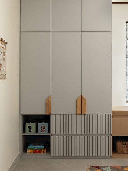 For a young collector of toys and books, I designed this bedroom with plenty of smart storage. The wardrobe features house-shaped handles and open cubbies at the bottom for easy access to their favorite things.