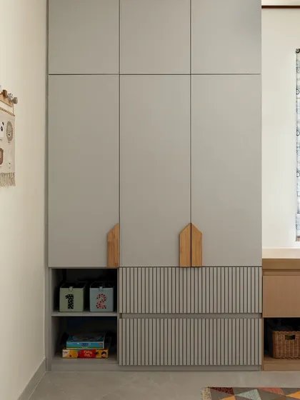 For a young collector of toys and books, I designed this bedroom with plenty of smart storage. The wardrobe features house-shaped handles and open cubbies at the bottom for easy access to their favorite things.