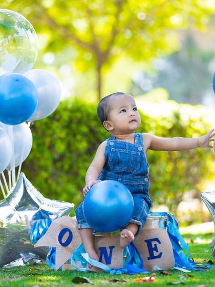 A first birthday picnic in the park! This setup with balloons and a "ONE" banner creates a festive and fun atmosphere for an outdoor shoot.