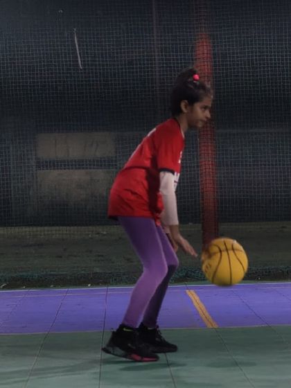 A young girl practices her dribbling technique. We ensure every player, regardless of age or gender, gets dedicated coaching on fundamental basketball skills.