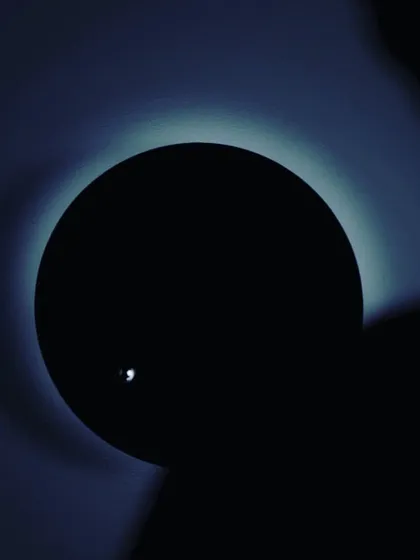 A dramatic, artistic photograph of the STORY clock in the dark. The levitating sphere catches the light, resembling a moon orbiting a planet, perfectly illustrating its concept of visualizing time's journey.