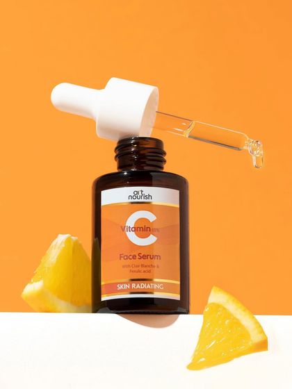 A simple yet effective composition. The Vitamin C serum bottle is propped up with fresh orange wedges, instantly connecting the product to its key ingredient and benefit. The clean lines keep it feeling modern.