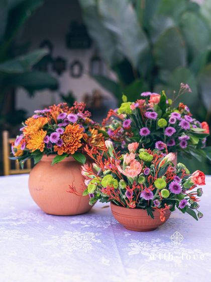 Small terracotta pots with colorful flowers, used as simple and charming centerpieces for a Pellikuthuru lunch.
