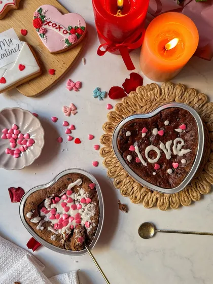 Two heart-shaped cookie cakes fresh from the oven, one decorated with "love" in icing and the other with heart sprinkles. This shows the fun and personalization of my DIY kit.