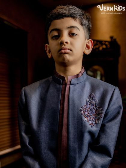 A portrait shot of our young model in the layered Indo-western set. His serious expression adds a touch of high-fashion drama to this elegant and handcrafted outfit.