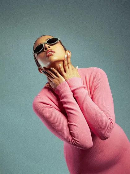 A high-fashion studio shot with a pop of color. The model's pose and the stark lighting against a cool blue background create a modern, editorial feel.