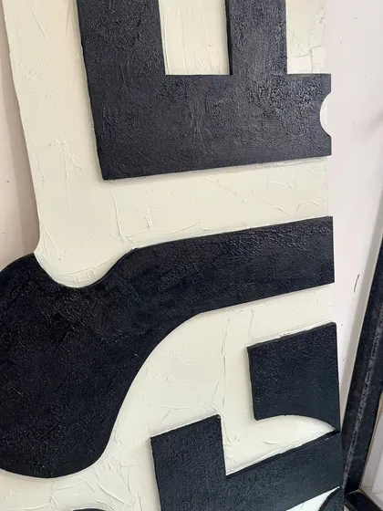 A close-up of a custom-shaped textured piece in black and white. The sharp edges and heavy texture make it a very graphic and modern artwork.