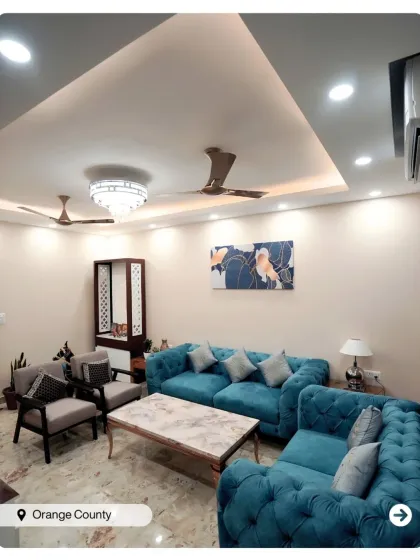 A comfortable and chic living room in Orange County with a tufted teal sofa. The design is simple yet elegant, with a focus on creating a welcoming atmosphere.