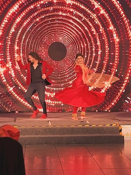 A full-stage shot of a duet, capturing the energy and vibrant backdrop.