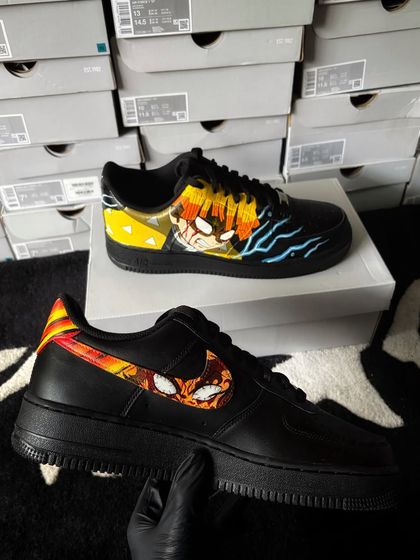 A pair of black Nike Air Force 1s customized with Demon Slayer art, showing Tanjiro on one swoosh and Zenitsu on the other.