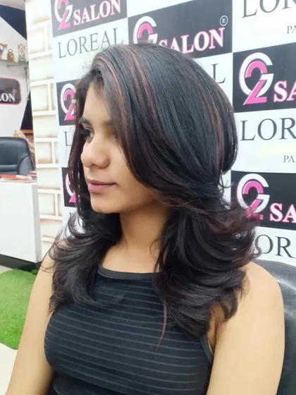 This layered haircut is enhanced with subtle red and brown highlights, which add depth and draw attention to the beautiful shape of the cut.