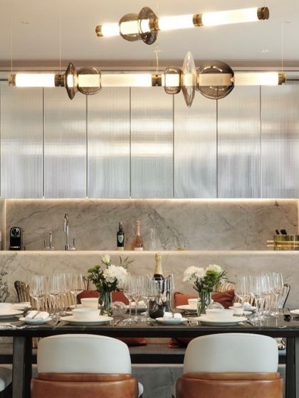 The Luna series is shown illuminating a beautifully set dining table, its warm light reflecting off the marble countertop and glassware. This scene illustrates how the right lighting can enhance the ambiance of an elegant dining experience.