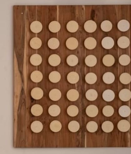 The finished wall installation in a client's dining room. The grid of stoneware discs in varying shades creates a subtle, textured focal point that complements the modern interior.