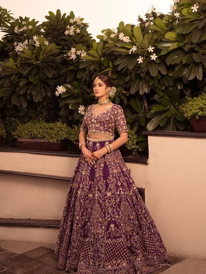 The bride's pose showcases the grandeur and elegance of this purple and gold ensemble.