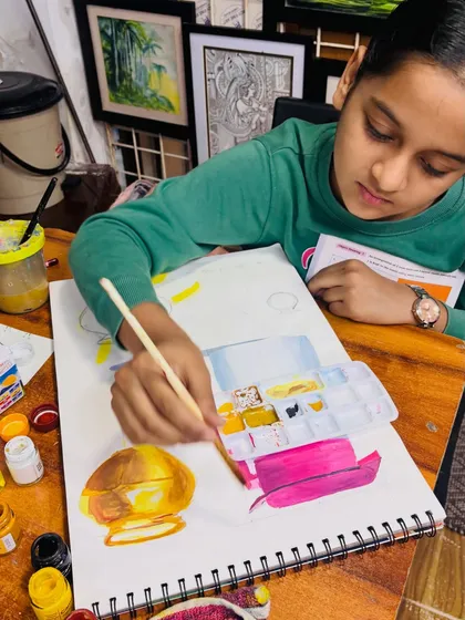 A young artist fully engaged in her work, mixing colors to accurately paint a metallic pot. We ensure each student gets personal attention to guide them through challenging techniques like rendering reflective surfaces.