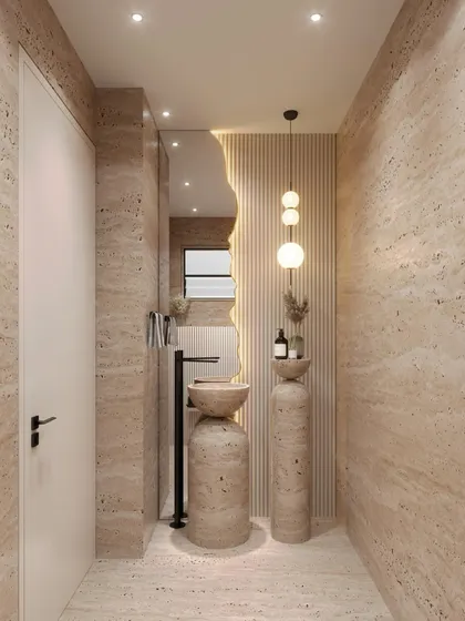 A different angle of the travertine powder room, showing the seamless transition from wall to floor. The pendant lighting and fluted wall panel behind the sink add layers of texture and sophisticated detail.