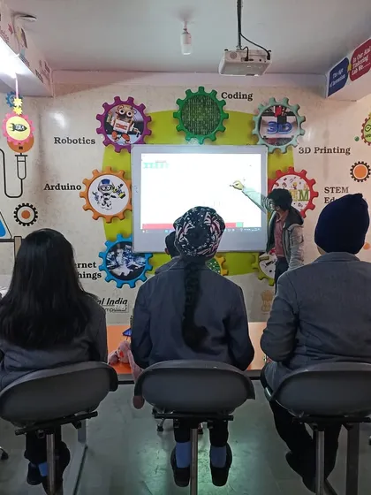 An instructor leads a session in a vibrant Atal Tinkering Lab. The walls, decorated with concepts like coding, 3D printing, and robotics, create an immersive atmosphere that encourages creative thinking and problem-solving.