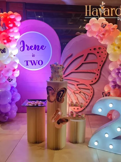 Another beautiful butterfly-themed party, this one for a second birthday. The decor features a large, elegant butterfly wing cutout and a soft, colorful balloon arrangement.