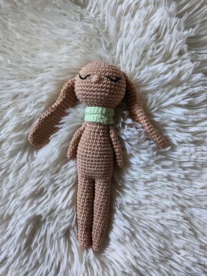 The sleepy bunny lying down on a soft white surface, perfect for a nap.