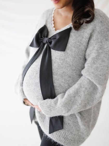 A close-up on the bump, beautifully presented like a gift with a large black bow, symbolizing the precious life within.