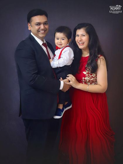 A classic family portrait. Dressed in elegant red and black, this family of three looks picture-perfect in this formal studio photoshoot.
