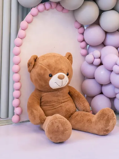 A giant, huggable teddy bear sits nestled within the pastel balloon decor, welcoming guests to the baby shower.