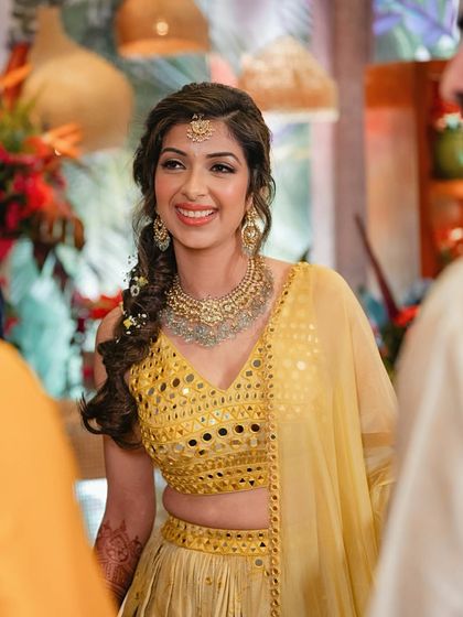 A beautiful braided hairstyle and glowing skin for this bride's Haldi. The makeup is minimal and radiant, perfect for a sun-filled outdoor event.