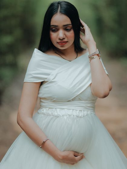 A close-up portrait of a mom-to-be in a classic white maternity gown. The elegant off-shoulder wrap is a timeless and flattering style.