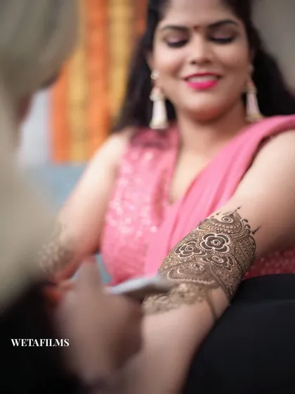 Capturing the intricate art of Mehndi. This shot focuses on the beautiful henna design being applied, a key part of the pre-wedding preparations and a symbol of joy and beauty.