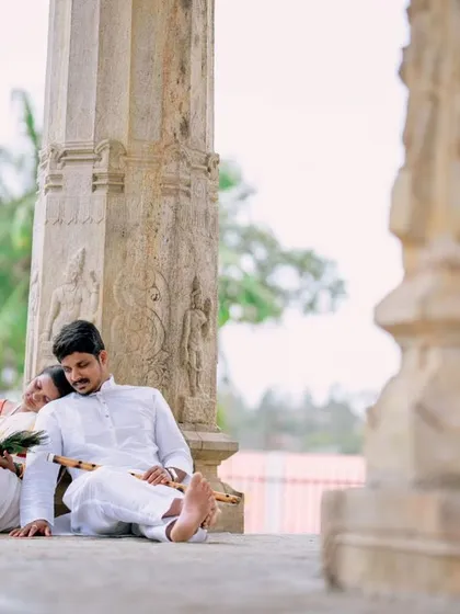 A peaceful moment of rest during a temple photoshoot. The couple's traditional white outfits create a serene and classic look against the stone architecture.