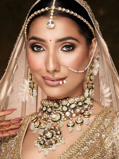 The epitome of bridal elegance. This portrait captures a moment of quiet grace, with soft lighting that enhances the bride's glowing skin and the intricate details of her golden lehenga and polki jewelry. It's a timeless vision of modern bridal beauty.
