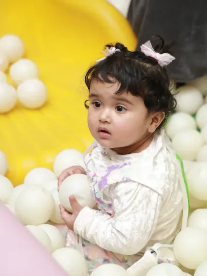 A curious toddler explores the textures and shapes of the balls in our clean and safe ball pit.