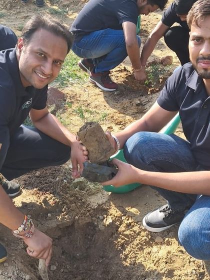 Two smiling volunteers from Bacardi pose with the rocks they are using to protect a newly planted sapling. This technique helps retain moisture in the soil.