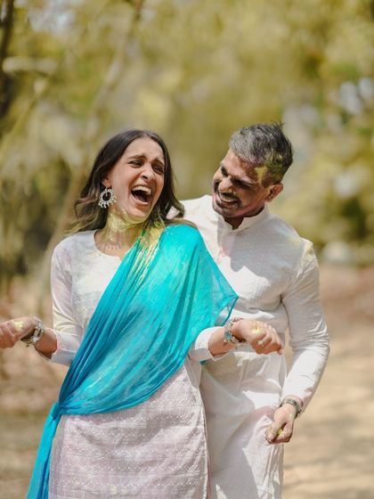 A beautiful, candid photo of a couple sharing a huge laugh, covered in colors. This image perfectly encapsulates the fun and spirit of a unique pre-wedding celebration.