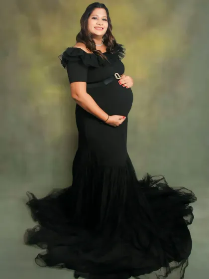 Our black off-the-shoulder mermaid gown is a client favorite. It offers a timeless, elegant look that beautifully accentuates the baby bump, perfect for both studio and outdoor settings.